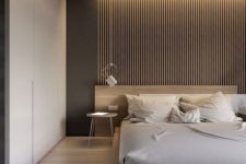 a chic minimal bedroom with a wooden bed, a wooden slabs, built-in lights, sleek storage space and sconces