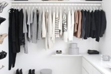 a cool minimalist white closet with a holder for hangers, a sideboard, open shelves and boxes