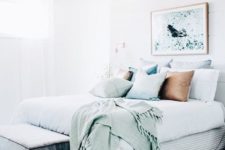 a cute coastal bedroom in neutrals, with seaside-inspired bedding and an artwork is very welcoming