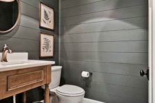 a farmhouse powder room with grey beadboard walls, a pendant lamp, a tile floor and a vintage wooden vanity plus artworks