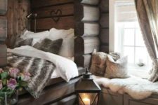 a gorgeous chalet bedroom clad with wood, with a bed in a niche, a windowsill bench with storage is super welcoming