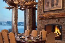 a gorgeous chalet dining room with a built-in fireplace, vintage furniture, an antler chandelier and a fantastic view of the mountains