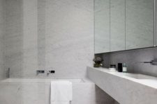a grey minimalist bathroom with a bathtub, a shower space with a glass divider and a large mirror plus a floating vanity