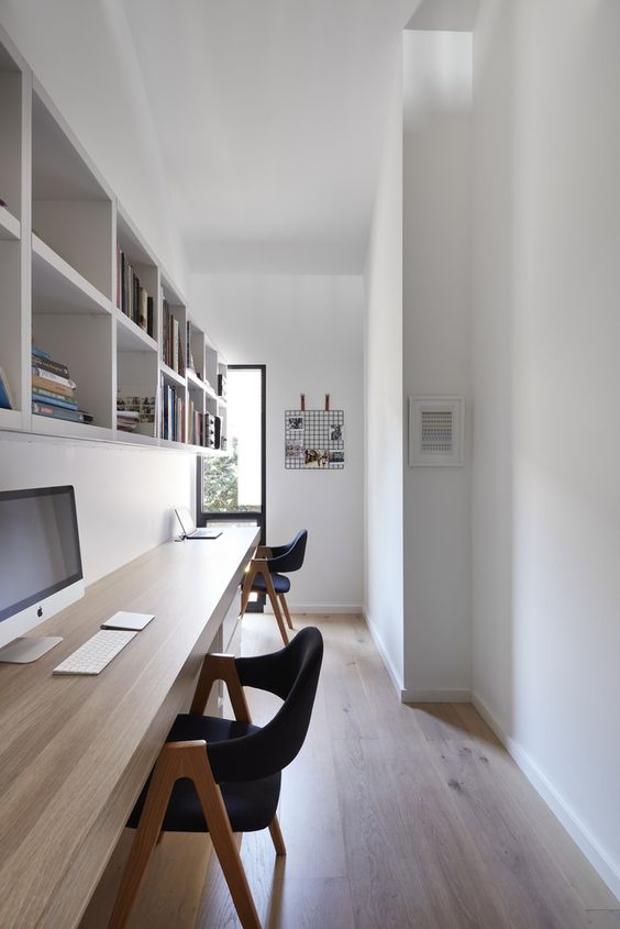 a long and narrow shared minimalist home office with a floating desk, open shelves, black chairs and a grid