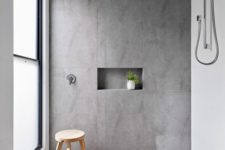 a minimalist bathroom with grey and white large scale tiles, a frosted glass window and simple fixtures