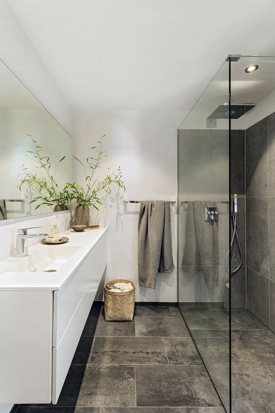 a minimalist bathroom with large scale grey tiles, a shower space, a floating white vanity, white walls and a large mirror