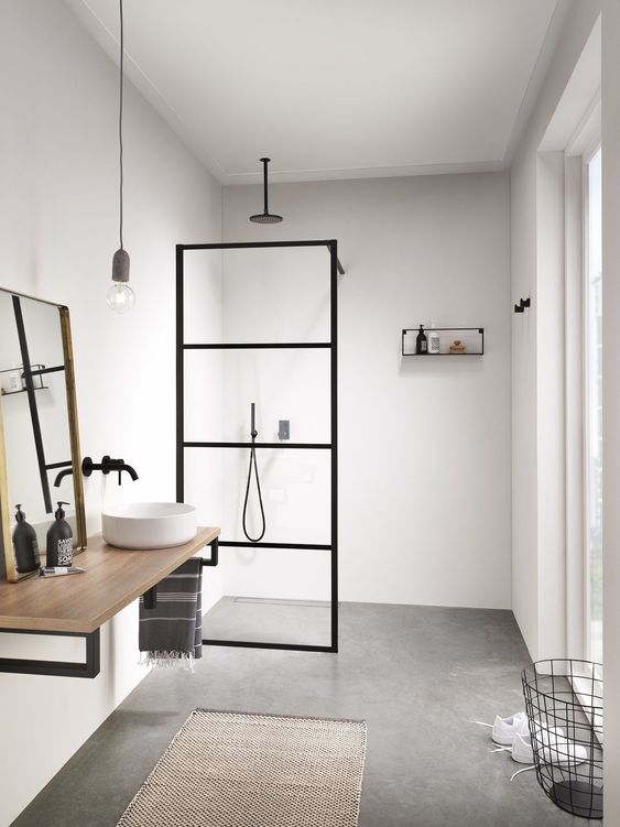 a minimalist bathroom with neutral walls, a concrete floor, a simple vanity, a mirror and a pendant bulb