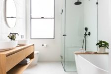 a minimalist bathroom with skinny tiles on the wall, neutral tiles on the floor, a glass enclosed shower space, a bathtub and a floating vanity