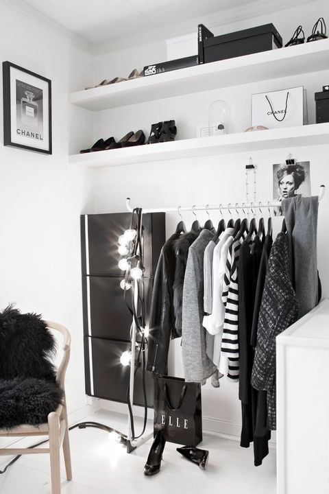 a minimalist black and white closet with open shelves, a holder with hangers, a sideboard, lights and touches of black