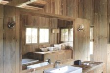 a minimalist chalet bathroom all clad with light-colored wood, with a sink and a large wooden vanity