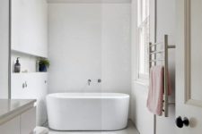 a minimalist neutral bathroom with various tiles, a floatign vanity, a bathtub, a window and some pretty textiles