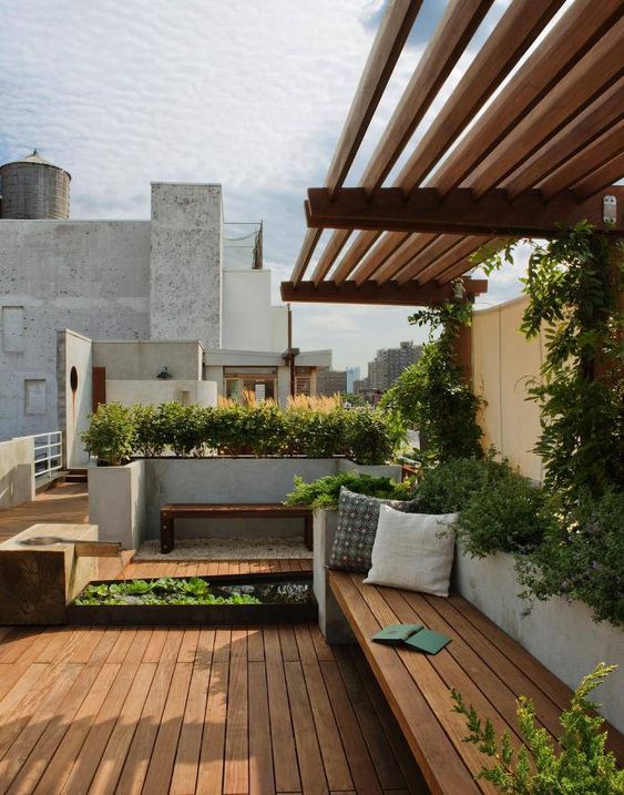 a minimalist terrace with a wooden deck, a wooden bench, lots of growing greenery and a waterfall for a zen feel