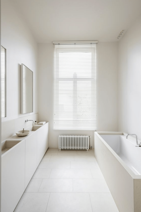 A minimalist warm colroed bathroom in creamy and tan, with tiles on the floor and a plywood vanity and a bathtub clad with plywood