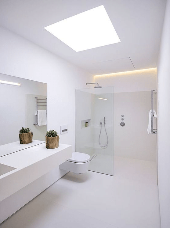 a minimalist white bathroom with a skylight and built-in lights, a sleek vanity, a shower with a glass partition and white appliances