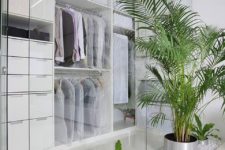 a minimalist white closet with glass doors, white drawers, holders for hangers and open shelves