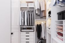 a minimalist white closet with lots of open storage compartments, drawers, shelves and built-in lights