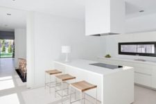 a minimalist white kitchen with sleek cabinets, a large hood and a kitchen island plus a cool long window backsplash for more light