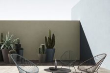 a minimalsit terrace with a black coffee table, wicker chairs and succulents and cacti in statement planters