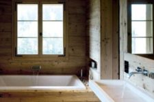 a modern chalet bathroom all clad with wood, a wall-mounted sink, a built-in tub and modern faucets
