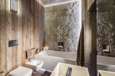 a modern chalet bathroom clad with reclaimed wood, with a stone wall, modenr appliances and built-in lights