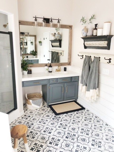 a modern farmhouse bathroom with a large mirror, a grey vanity, a shower, a tile floor and some cool decor