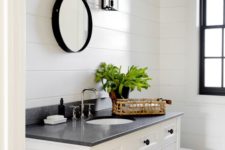 a monochromatic farmhouse powder room clad with white beadboard, with a two tone vanity, a vintage mirror and greenery