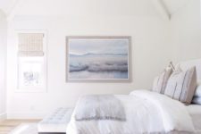 a serene and airy coastal bedroom in neutrals, with a large artwork, woven shades and printed textiles is super cool