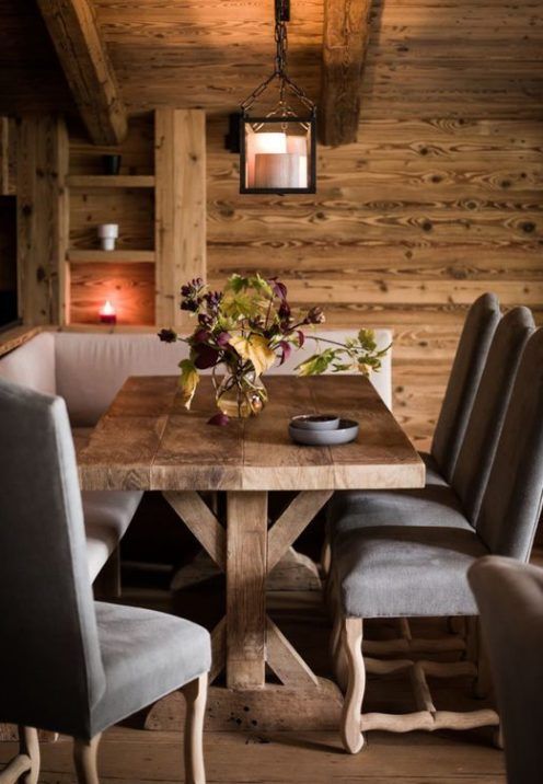 a small and cozy chalet dining nook with a corner sofa, elegant vintage chairs and candles and candle lanterns