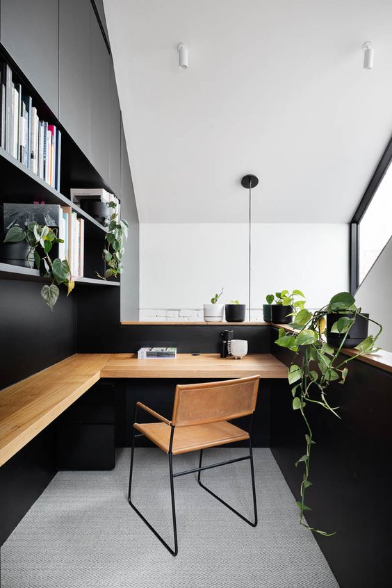 a stylish minimalist home office in black, with open shelves, a floating desk, a leather chair and lots of potted greenery