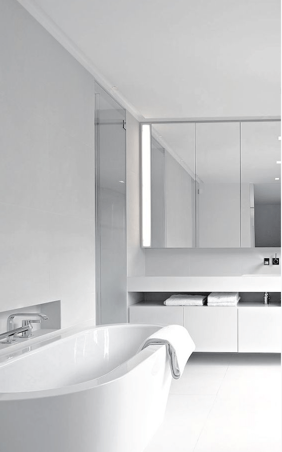 a white minimalist bathroom with a mirrored cabinet, a floating vanity, a white tub, stainless steel fixtures