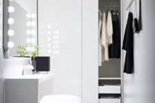 a white minimalist closet with a wardrobe with sliding doors, some hooks and a vanity with an ottoman