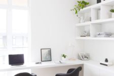 an airy white home office with a large open shelf, a large shared desk and black chairs