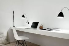 an ultra-minimalist shared home office with a white floating desk, black sconces and a white chair