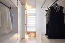 an ultra-minimalist white closet with large dressers, open shelves, holders for hangers and boxes