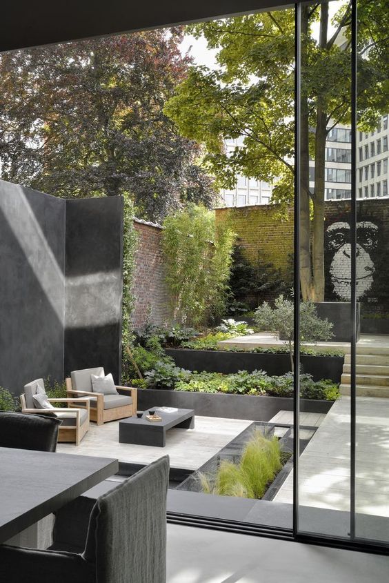an ultra-modern monochromatic backyard with greenery all around, modern furniture