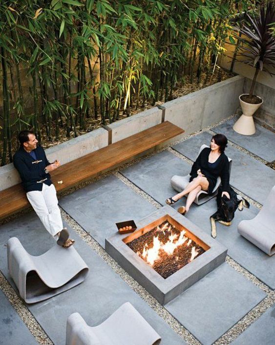 an ultra modern patio with concrete pavements, bamboo in concrete planters and a fire pit in the center