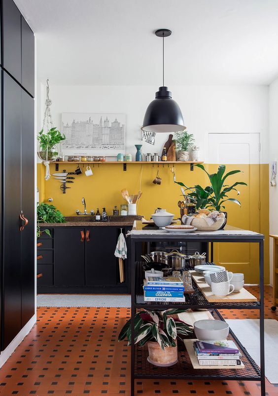 a black kitchen with stone countertops and a mustard color block wall for a bright touch