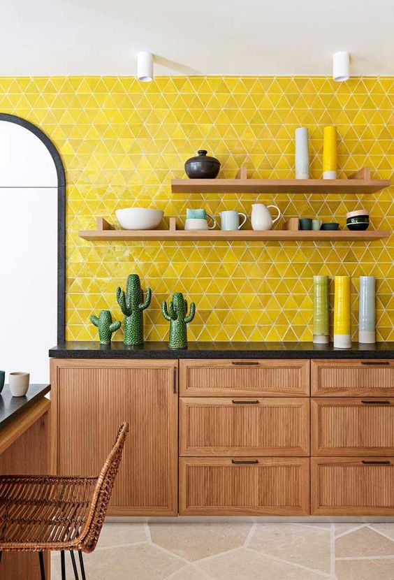 a mid century modern kitchen with wooden cabinets and black countertops plus lemon yellow tiles on the wall