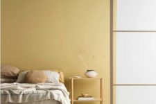 04 a minimalist bedroom with light yellow walls, simple wooden furniture and neutral textiles is super chic
