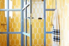 04 a super bright yellow tile bathroom with a glazed shower door with blue framing for a contrasting look