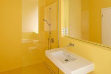06 a minimalist sunny yellow bathroom done sleek and plain, with a statement mirror and a floating sink