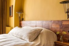 06 a rustic bedroom with warm yellow walls, a wooden bed and nightstands and heavy mustard curtains