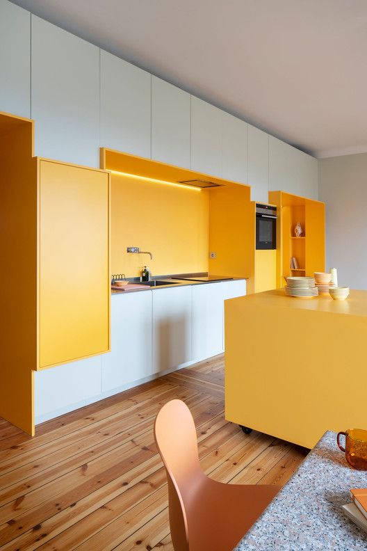 a bright kitchen done in white with sunny yellow niches and a kitchen island is very cheerful