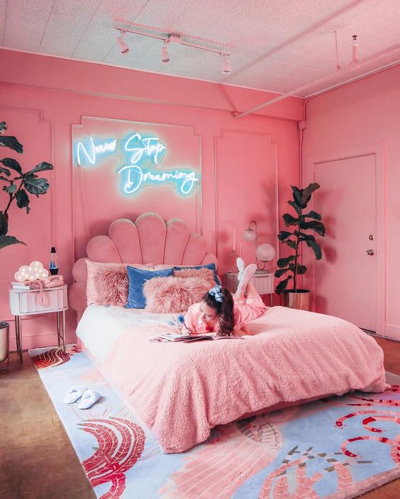 a glam pink bedroom with bright pink walls, a pink upholstered bed and pink nightstands plus a whimsy rug with pink
