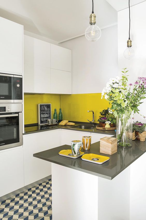 a small white and grey kitchen with plain cabinets and a sleek mustard tile backsplash for a touch of color