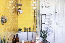 13 a catchy neutral bathroom with a grey tile floor and a sunny yellow tile backsplash around the bathtub