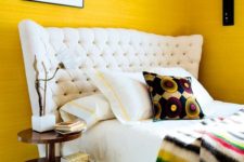 13 a cheerful whimsical bedroom with sunny yellow walls, a white upholstered bed and touches of black