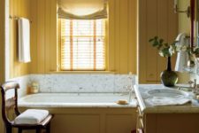 14 a charming vintage bathroom with mustard beadboard walls, a vanity and a bathtub clad with mustard wood and neutrals