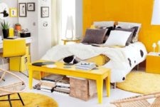 21 a bold modern bedroom with a yellow panel wall, a yellow bench, rugs, chair and a cabinet looks extra bright