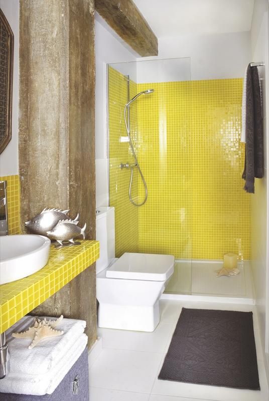 a bright bathroom with yellow tiles in the shower and a bright tile vanity, white large scale tiles and industrial wooden beams